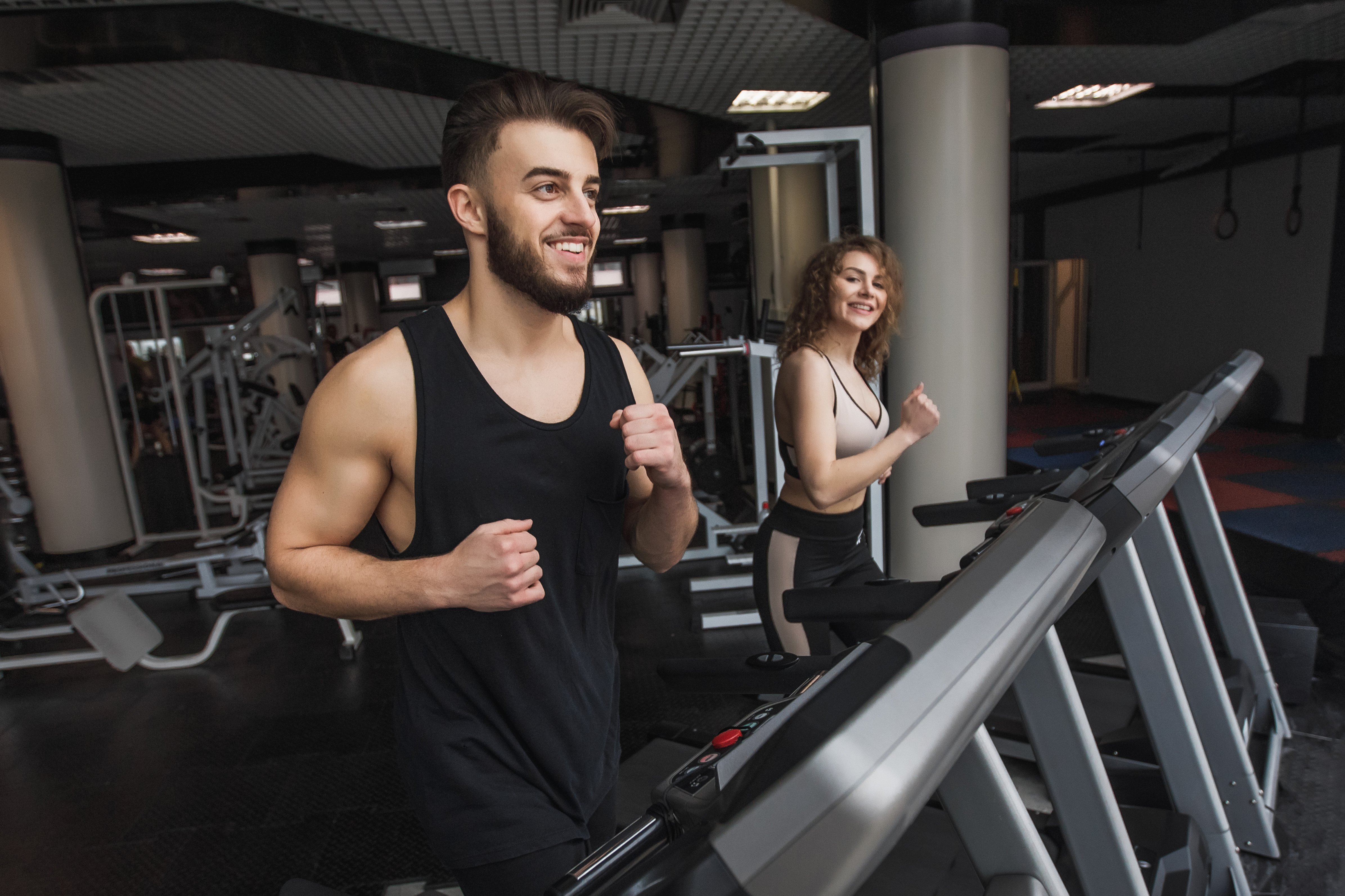 retrato-de-jovem-casal-de-esportes-fazendo-exercicios-aerobicos-em-uma-academia-moderna